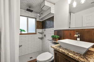 Professionally tiled bathroom featuring a shower stall and vanity