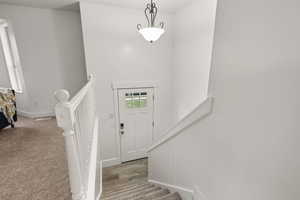 Foyer entrance with stairs and light carpet