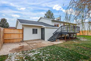 Back of house with a fully fenced backyard, a patio area, roof with shingles, and a wooden deck
