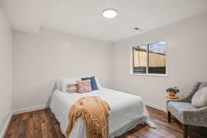 Bedroom with dark wood-style flooring and baseboards