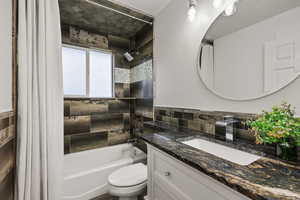 Bathroom featuring shower / tub combo, vanity, and decorative backsplash