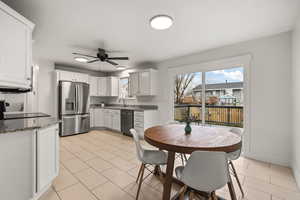 Kitchen featuring white cabinets, appliances with stainless steel finishes, dark stone countertops, a ceiling fan, and light tile patterned flooring