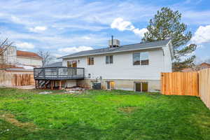 Back of house featuring a fenced backyard, a deck, stairs, and a shingled roof