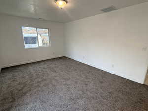 Spare room featuring dark colored carpet and a textured ceiling