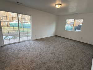 Carpeted empty room featuring a textured ceiling and baseboards