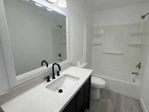 Bathroom featuring vanity, a textured wall, bathtub / shower combination, and light wood-style floors