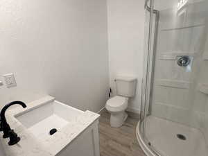 Full bathroom with vanity, a textured wall, light wood finished floors, and a shower stall