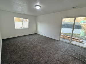 Empty room featuring a textured ceiling and dark carpet