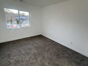 Unfurnished room featuring baseboards and dark carpet