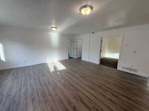Spare room featuring a textured ceiling and dark wood-style flooring