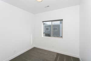 Empty room featuring baseboards and dark carpet