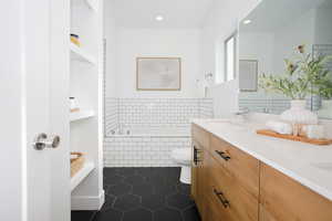 Bathroom with double vanity, a bath, dark tile patterned flooring, and recessed lighting