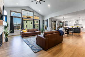Living room featuring recessed lighting, a fireplace, light wood-style floors, a chandelier, and high vaulted ceiling