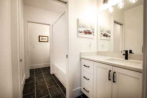 Bathroom featuring vanity,  shower combination, and dark tile patterned flooring