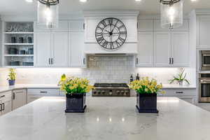 Kitchen featuring decorative backsplash, decorative light fixtures, white cabinets, and recessed lighting