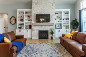 Living area featuring a stone fireplace and light wood-style floors