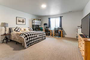 Bedroom featuring light carpet and an office area