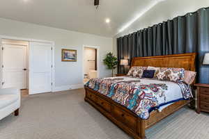 Bedroom with lofted ceiling, connected bathroom, light colored carpet, a ceiling fan, and recessed lighting