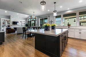 Kitchen with hanging light fixtures, white cabinetry, dark cabinetry, recessed lighting, and open floor plan