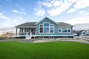 Rear view of property with a yard, a mountain view, and a shingled roof