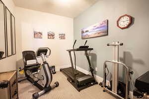 Exercise area featuring baseboards and light carpet