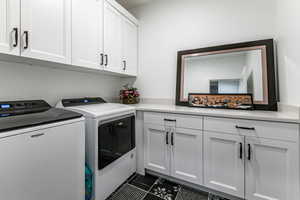 Washroom featuring cabinet space, independent washer and dryer, and dark tile patterned flooring