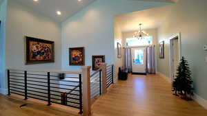 Foyer featuring light wood finished floors, a chandelier, and high vaulted ceiling