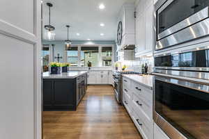 Kitchen with stainless steel appliances, white cabinets, pendant lighting, light stone counters, and recessed lighting
