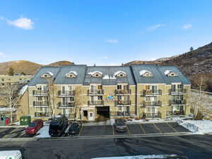 View of apartment building / complex featuring a mountain view and uncovered parking