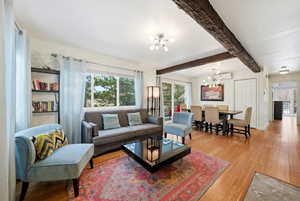 Living room with beamed ceiling, wood-type flooring, and a chandelier
