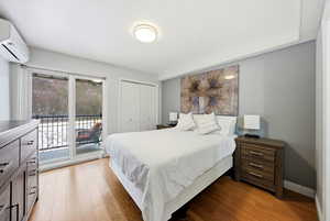 Bedroom featuring access to outside, a closet, light wood-style flooring, and an AC wall unit