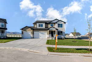View of front facade with stone siding, driveway, and an attached garage