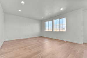 Empty room with light wood-type flooring and recessed lighting