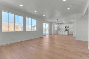 Unfurnished living room featuring a chandelier, recessed lighting, and light wood-type flooring