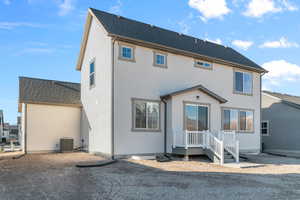 Back of house with a shingled roof and stucco siding