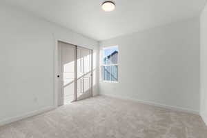Unfurnished room featuring light carpet and baseboards