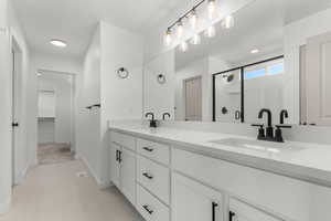Full bathroom with a stall shower, double vanity, and a walk in closet