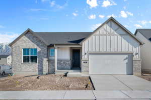 View of front of property featuring covered porch, board and batten siding, an attached garage, concrete driveway, and brick siding