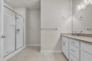 Full bath featuring double vanity, a shower stall, and light tile patterned floors