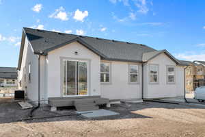 Back of house with stucco siding, roof with shingles, entry steps, and a patio area