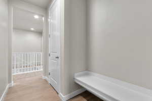 Corridor with light wood-style flooring, recessed lighting, and an upstairs landing