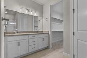 Bathroom with double vanity, a shower stall, a walk in closet, light tile patterned flooring, and light colored carpet