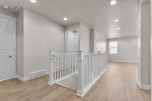 Corridor featuring an upstairs landing, recessed lighting, and light wood-style floors