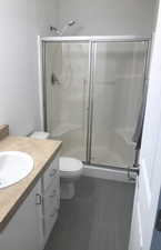 Full bathroom with vanity, a shower stall, and dark floors