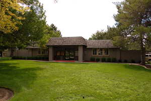 Rear view of house with a lawn and mansard roof