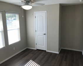 Spare room with dark wood-style floors and a ceiling fan