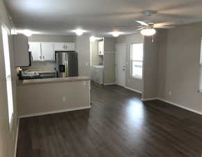 Kitchen featuring white cabinetry, stainless steel refrigerator with ice dispenser, a peninsula, separate washer and dryer, and light countertops