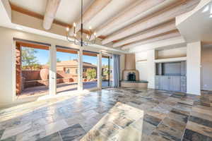 Unfurnished living room with beamed ceiling, recessed lighting, a chandelier, and stone tile floors