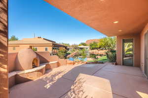 View of patio featuring a water view and a fireplace with raised hearth