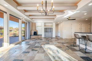 Unfurnished living room with recessed lighting, beam ceiling, a chandelier, stone tile floors, and a ceiling fan